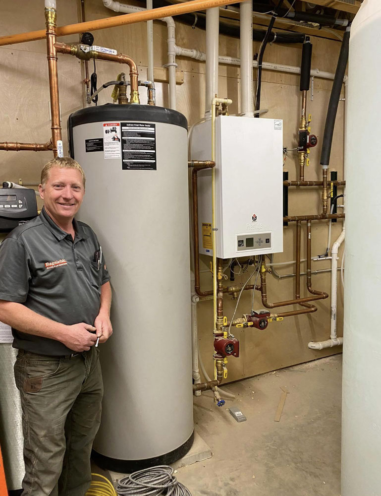 Lance standing next to the IBC high efficiency boiler and indirect fired water heater. The compact boiler is the heat source for the whole home and the domestic hot water.